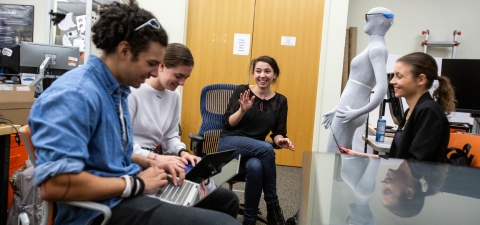 Students in a graduate research lab collaborating with laptops.